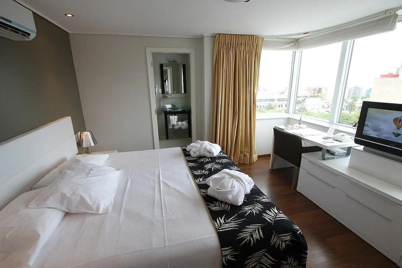 dormitorio_cama_baño_ventana_tv_hotel_regency_golf.webp